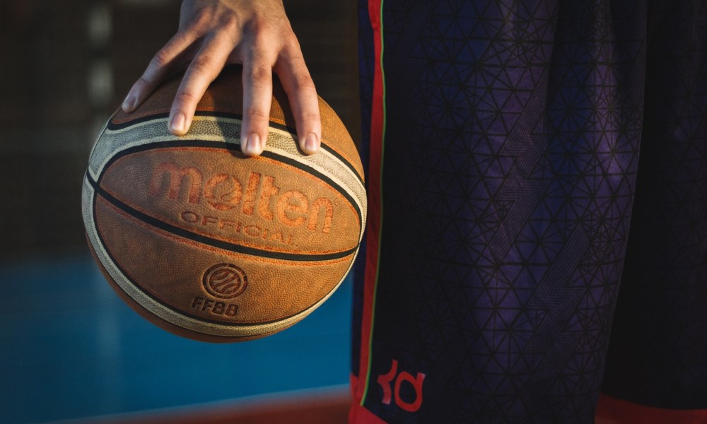 Hand gripping basketball against black background